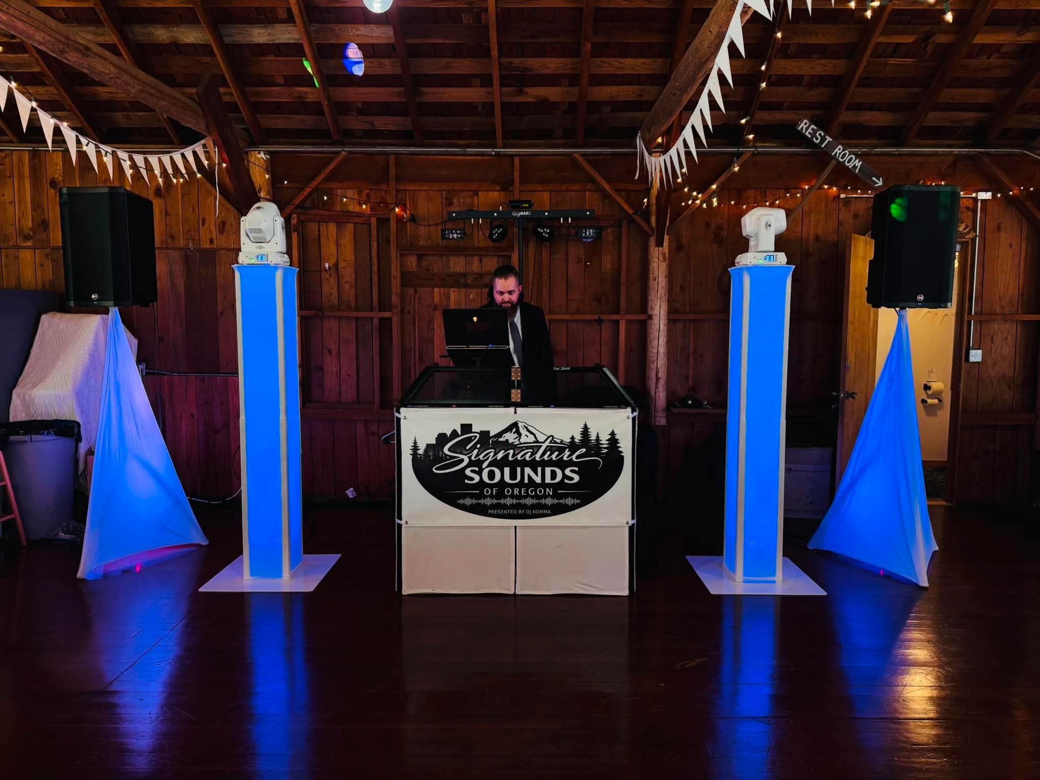 Signature Sounds of Oregon DJ booth with blue uplighting and moving heads at a barn wedding reception